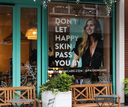 A large format print design with an image of a siling woman and window film text saying 'don't let happy skin pass you by' for Pai Skincare.