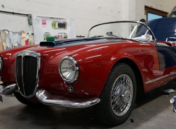Vintage car with blue and red paintwork in wrapping workshop