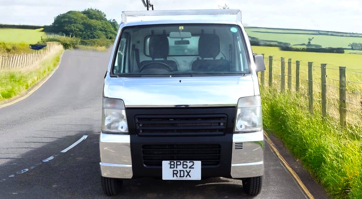 A vehicle wrapped in a chrome finish, on the road in the English countryside.