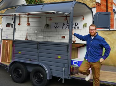 The Food Busker stands with his converted vehicle.