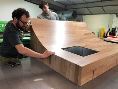 Two Raccoon team members build a printed board in the workshop, going beyond the typical large format printing company.