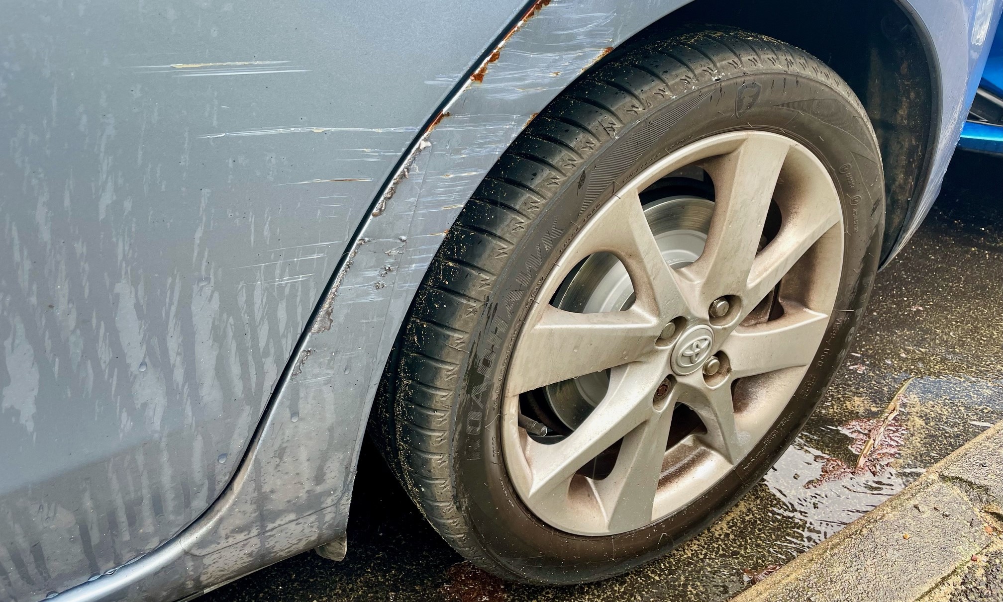 A car with scratches, dents and rust.